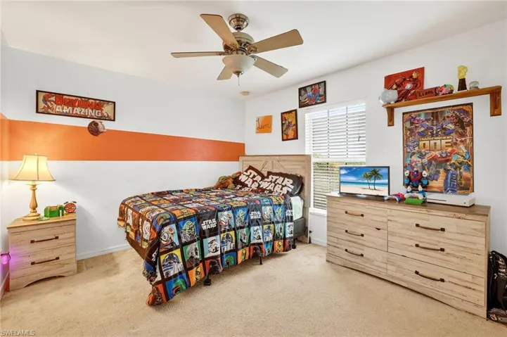 Carpeted bedroom featuring a ceiling fan and baseboards