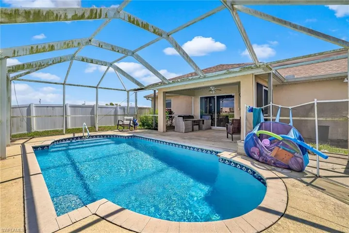 View of pool featuring a patio area, a fenced backyard, ceiling fan, and glass enclosure