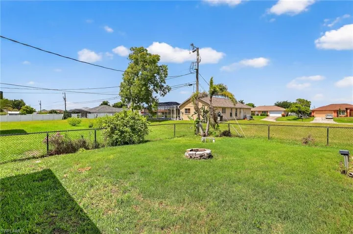 Fenced backyard featuring an outdoor fire pit and a residential view