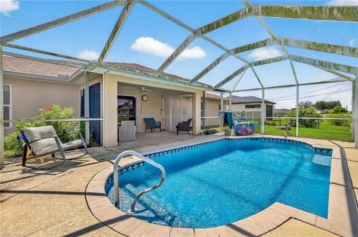 Outdoor pool featuring a patio area, a ceiling fan, and glass enclosure