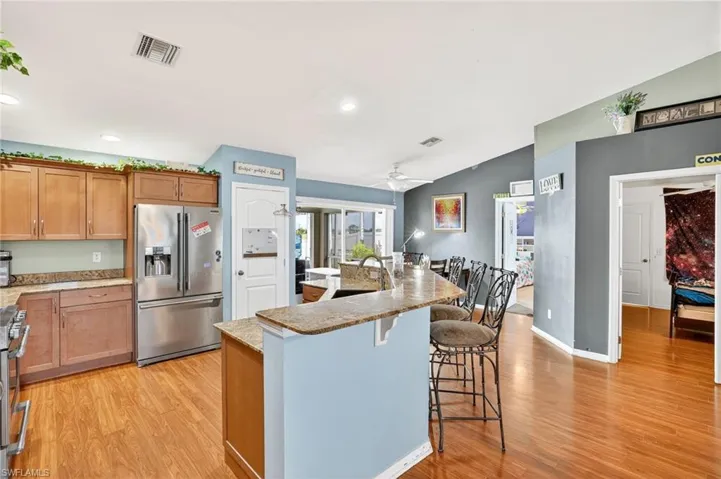 Kitchen with appliances with stainless steel finishes, light wood-style flooring, lofted ceiling, ceiling fan, and a breakfast bar area