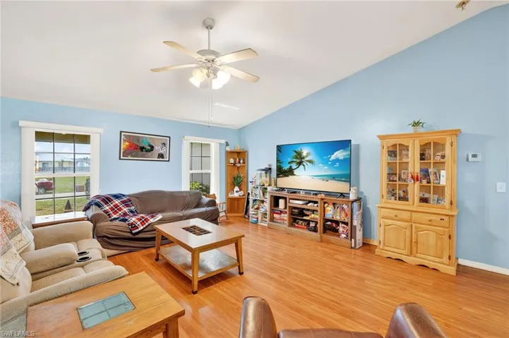 Living area featuring lofted ceiling, ceiling fan, and light wood-type flooring
