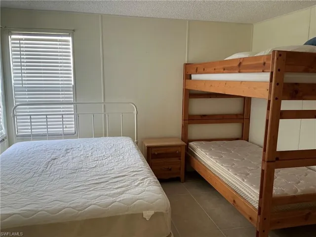Bedroom with tile patterned flooring, a textured ceiling, and a decorative wall