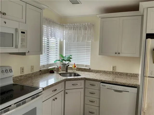 Kitchen featuring white appliances, a sink, and white cabinets