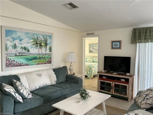Living area featuring light tile patterned floors and vaulted ceiling