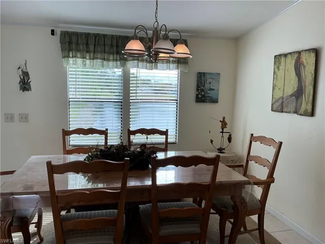 Dining area with crown molding, a chandelier, and light tile patterned flooring