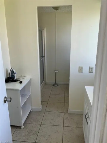 Bathroom with a stall shower, light tile patterned flooring, and vanity