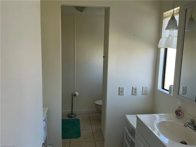 Bathroom featuring vanity, tile patterned flooring, toilet, and baseboards