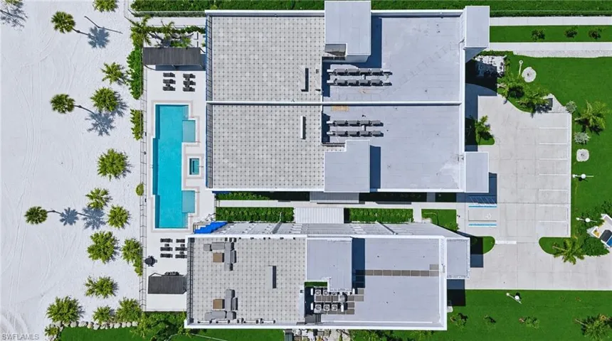 Modern multi-story building featuring a large rectangular pool with integrated spa, rooftop common areas, and a spacious parking lot - Virtually Edited Image