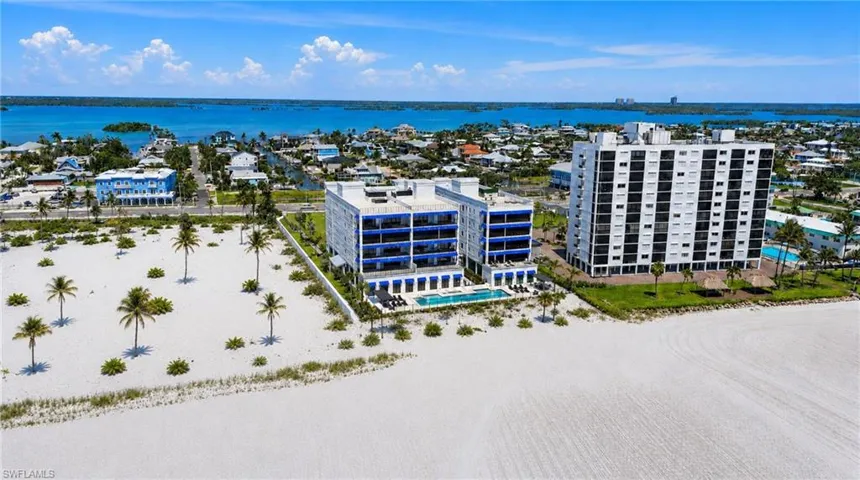 Coastal proximity, expansive white sand beach, multiple multi-story buildings, and direct water access - Virtually Edited Image