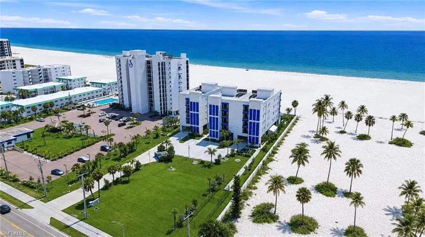 Coastal residential building with multiple balconies, adjacent to a wide sandy beach and ocean - Virtually Edited Image