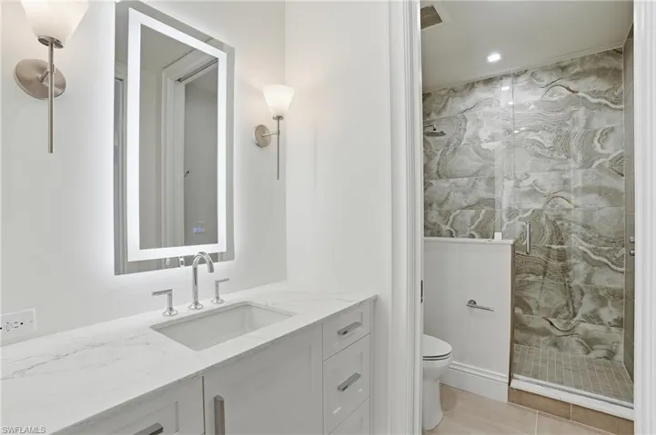 Bathroom featuring a marble finish shower, vanity, and recessed lighting