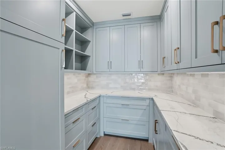 Kitchen featuring light stone countertops, light wood finished floors, and tasteful backsplash