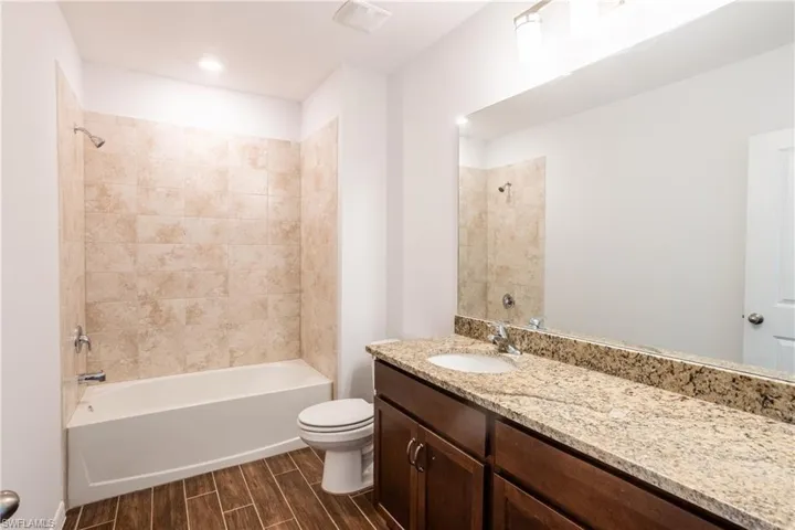 Full bathroom with tiled shower / bath, vanity, and toilet