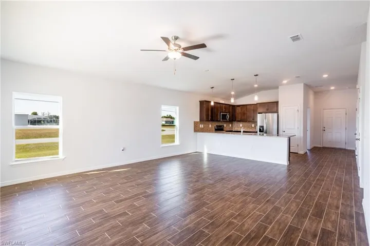 Unfurnished living room with dark wood-type flooring and ceiling fan