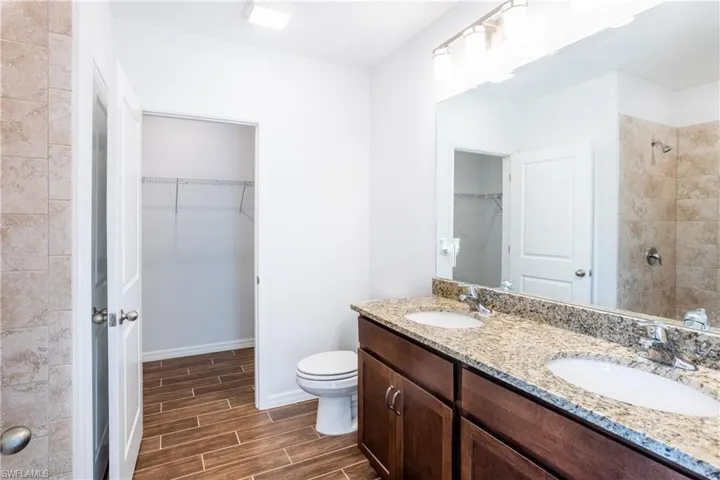 Bathroom with vanity, tiled shower, and toilet