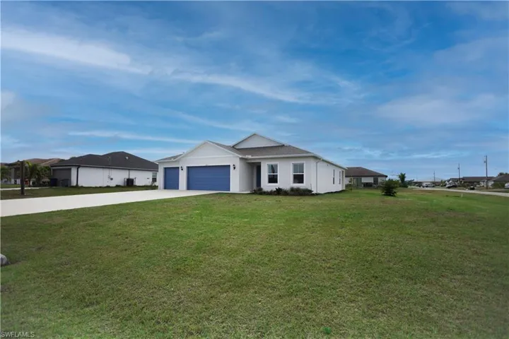 Florida-style house featuring a garage and a corner lot with big front lawn