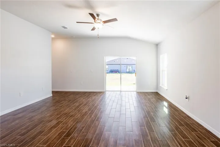 Unfurnished room featuring dark hardwood / wood-style flooring, vaulted ceiling, and ceiling fan