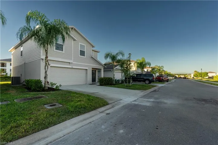 View of front facade featuring driveway, a garage, stucco siding, a front lawn, and a residential view