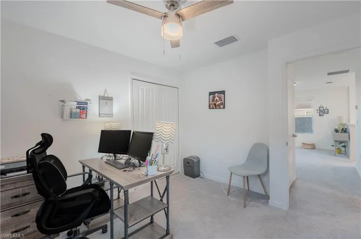 Office area with light colored carpet and ceiling fan