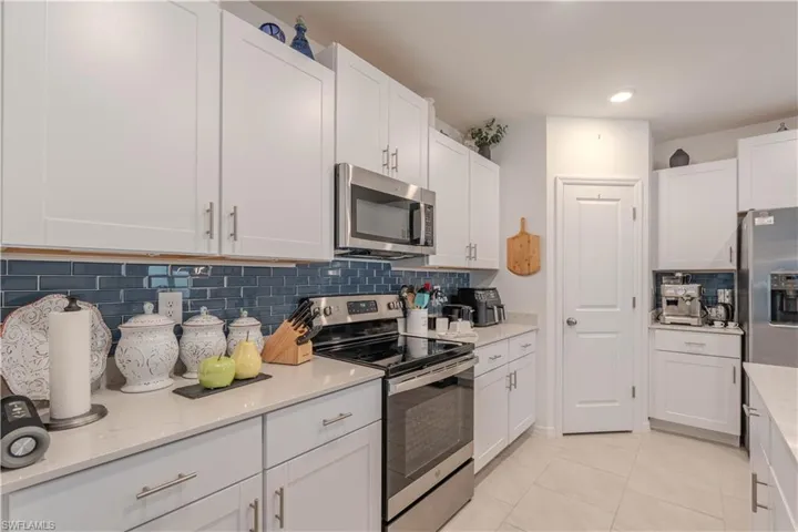 Kitchen featuring stainless steel appliances, tasteful backsplash, white cabinets, light tile patterned floors, and recessed lighting