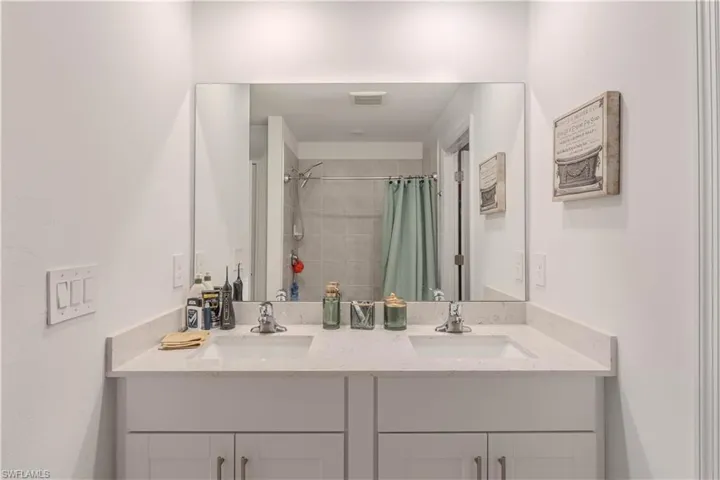 Full bath with double vanity and tiled shower