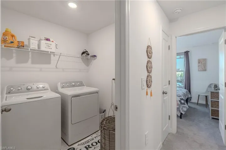 Washroom with washing machine and clothes dryer and light carpet