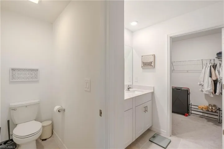Bathroom with vanity, light tile patterned floors, and a walk in closet