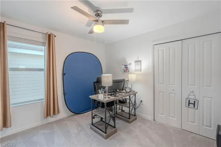 Office area featuring light colored carpet and ceiling fan