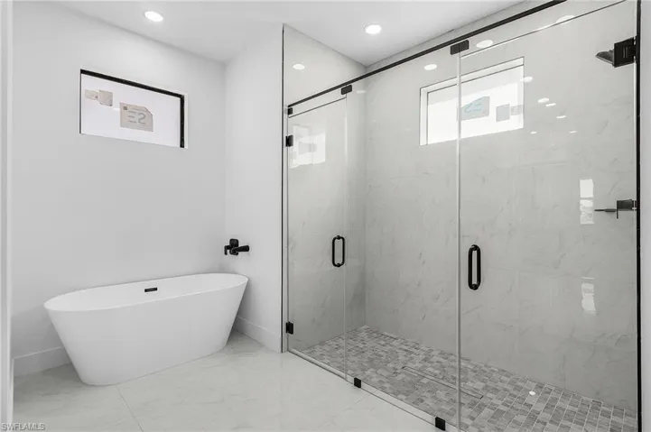 Bathroom with a marble finish shower, a soaking tub, marble finish flooring, and recessed lighting
