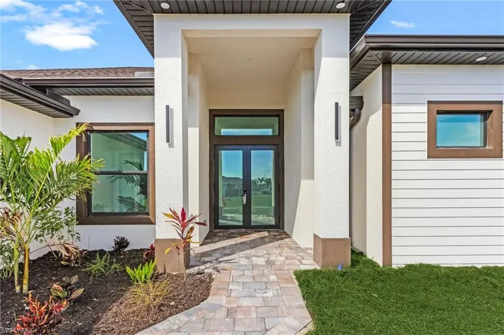 View of exterior entry featuring stucco siding and french doors