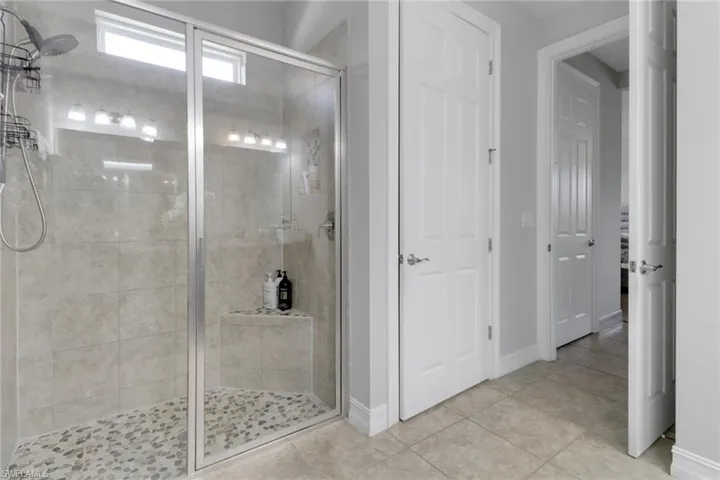 Bathroom with a shower stall, tile patterned floors, and baseboards