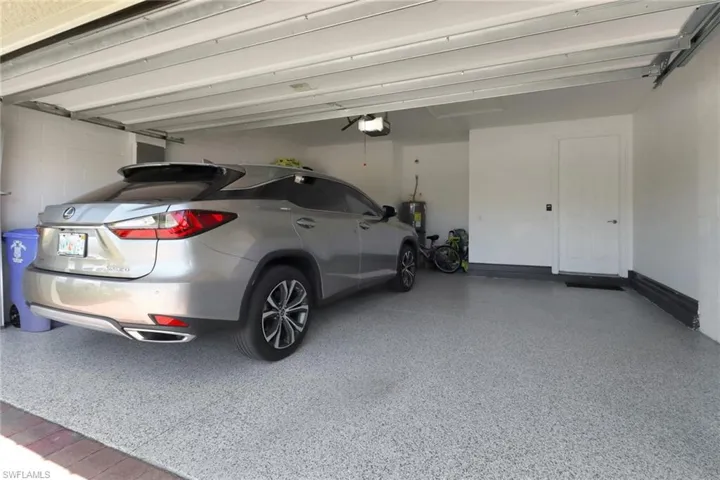 Garage with a garage door opener, baseboards, and water heater