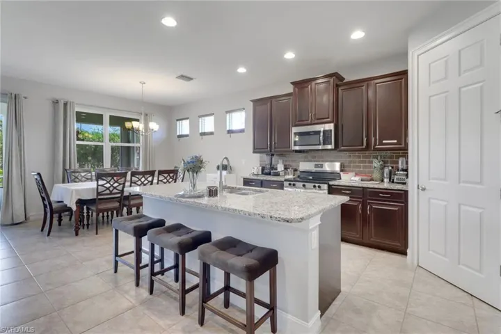 Kitchen featuring stainless steel appliances, a kitchen bar, an inviting chandelier, and light tile patterned flooring
