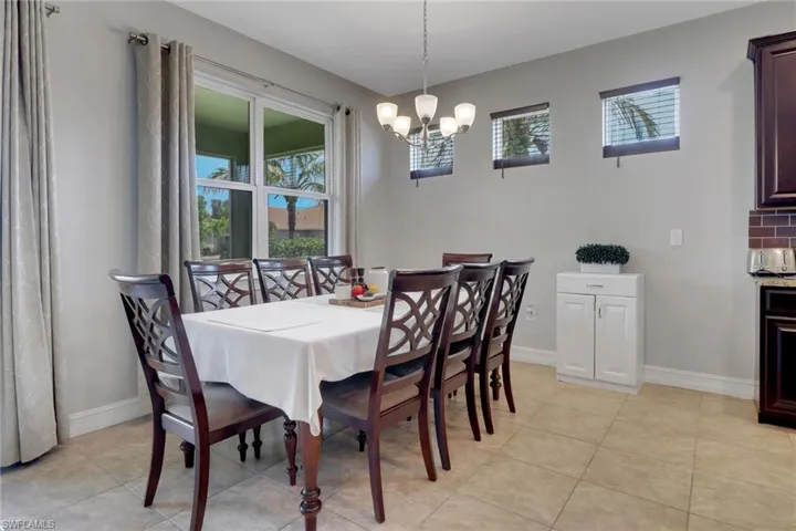 Dining area featuring light tile patterned flooring, an inviting chandelier, and baseboards