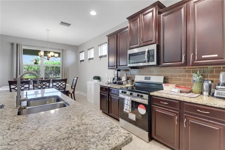 Kitchen featuring stainless steel appliances, a notable chandelier, a sink, and decorative backsplash