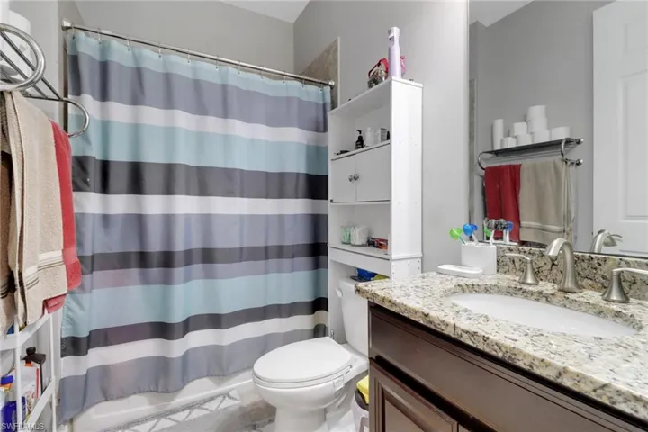Full bathroom with toilet, curtained shower, and vanity