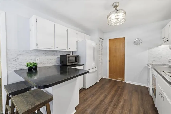 Kitchen featuring wood-finish flooring, white cabinetry, and a dark countertop breakfast bar
