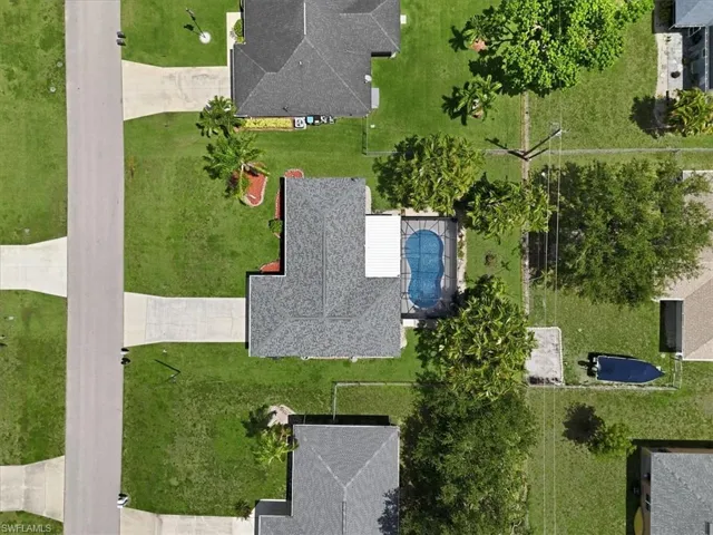 Aerial view highlighting a residential property with a shingle roof and an in-ground swimming pool