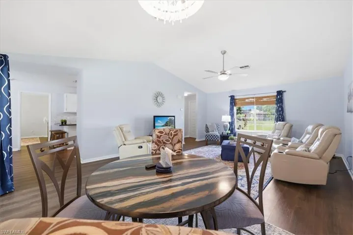 Open-concept living area with wood-finish flooring, vaulted ceilings, and a ceiling fan
