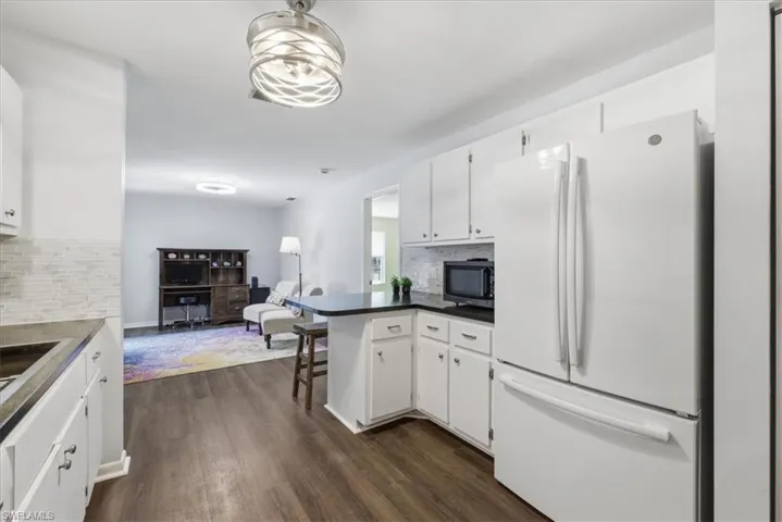 Kitchen featuring white cabinetry, dark countertops, a mosaic tile backsplash, and wood-finish flooring