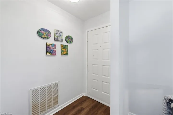 Entryway featuring wood-finish flooring, light grey wall paint, and white baseboards