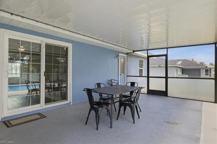 Screened outdoor living area with a textured concrete floor, light blue exterior wall, and white ceiling