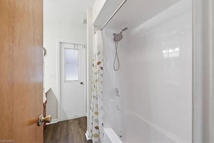 Bathtub and shower combination featuring a tiled surround and a handheld showerhead