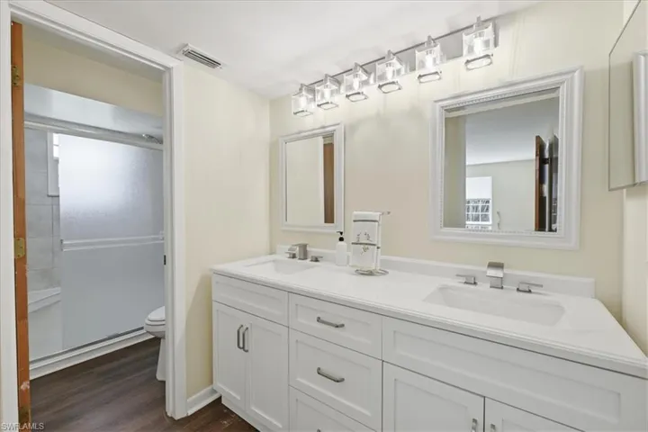 Double vanity with white cabinetry, integrated sinks, white countertops, and modern chrome fixtures