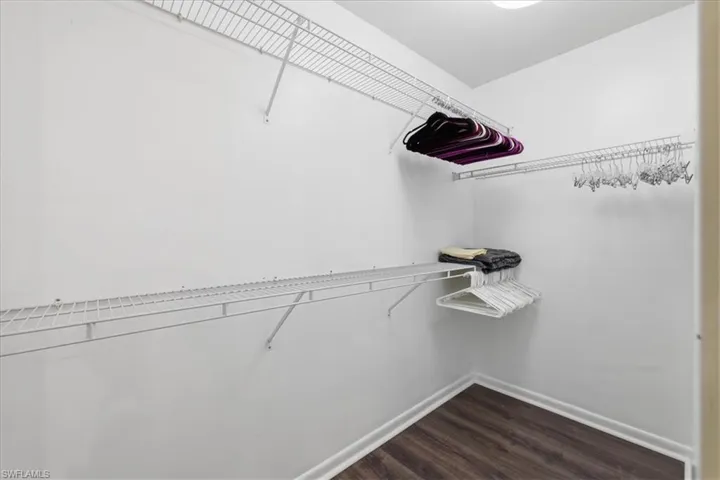 Walk-in closet featuring wood-finish flooring, white baseboards, and white wire shelving with integrated hanging rods