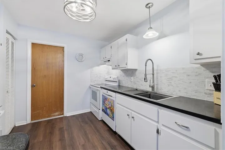 Kitchen featuring wood-finish flooring, white cabinetry, dark countertops, and a subway tile backsplash