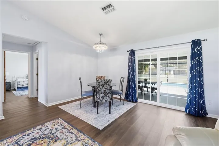 Dining area with wood-finish flooring, a contemporary chandelier, and white sliding glass doors