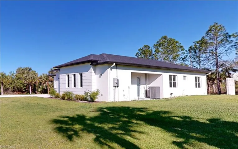 Back of house with stucco siding, central AC unit, and a yard