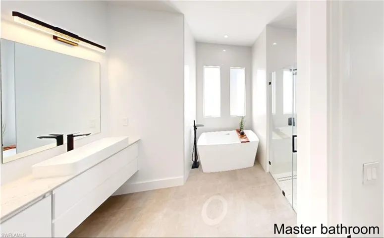 Bathroom featuring a stall shower, baseboards, a soaking tub, and vanity